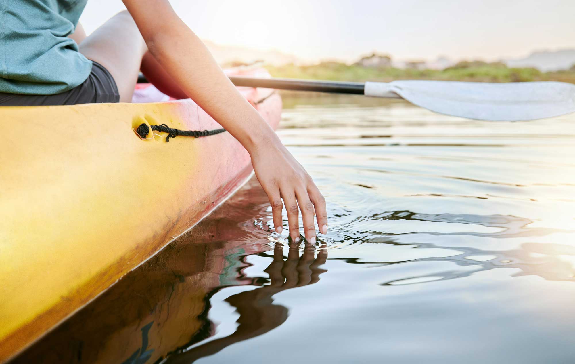 Closeup of female hands kayaking and feeling lake water during the day